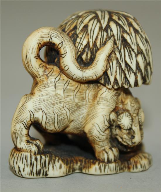 A Japanese stained ivory netsuke of a tiger crouching beneath a tree, 18th / 19th century, 4.2cm.